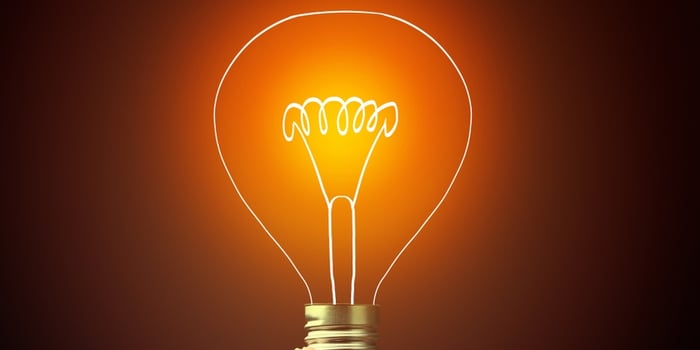 Hand holding light bulb on dark background, new idea concept