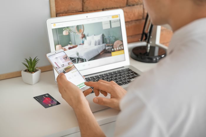 consumer making their way through the research stage of the consumer journey while searching on phone and laptop to compare businesses and products