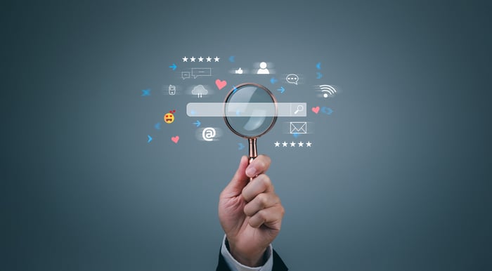 Hand holding magnifying glass with search bar and icons