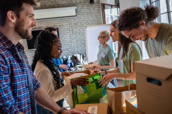 Employees showing Social Responsibility packing food and goods for charity showing Why Your Business Needs To Partner With a Charity