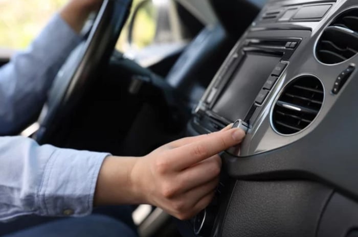 Person turning up volume in car showing the importance of understanding which dayparts your radio ad plays