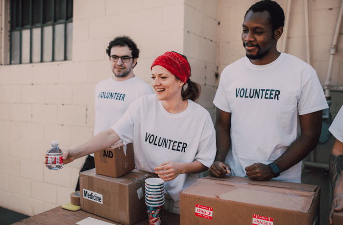 Three Volunteers standing behind a table passing out bottled water