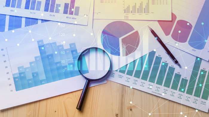 Spread sheets on first party data on table with magnifying glass 